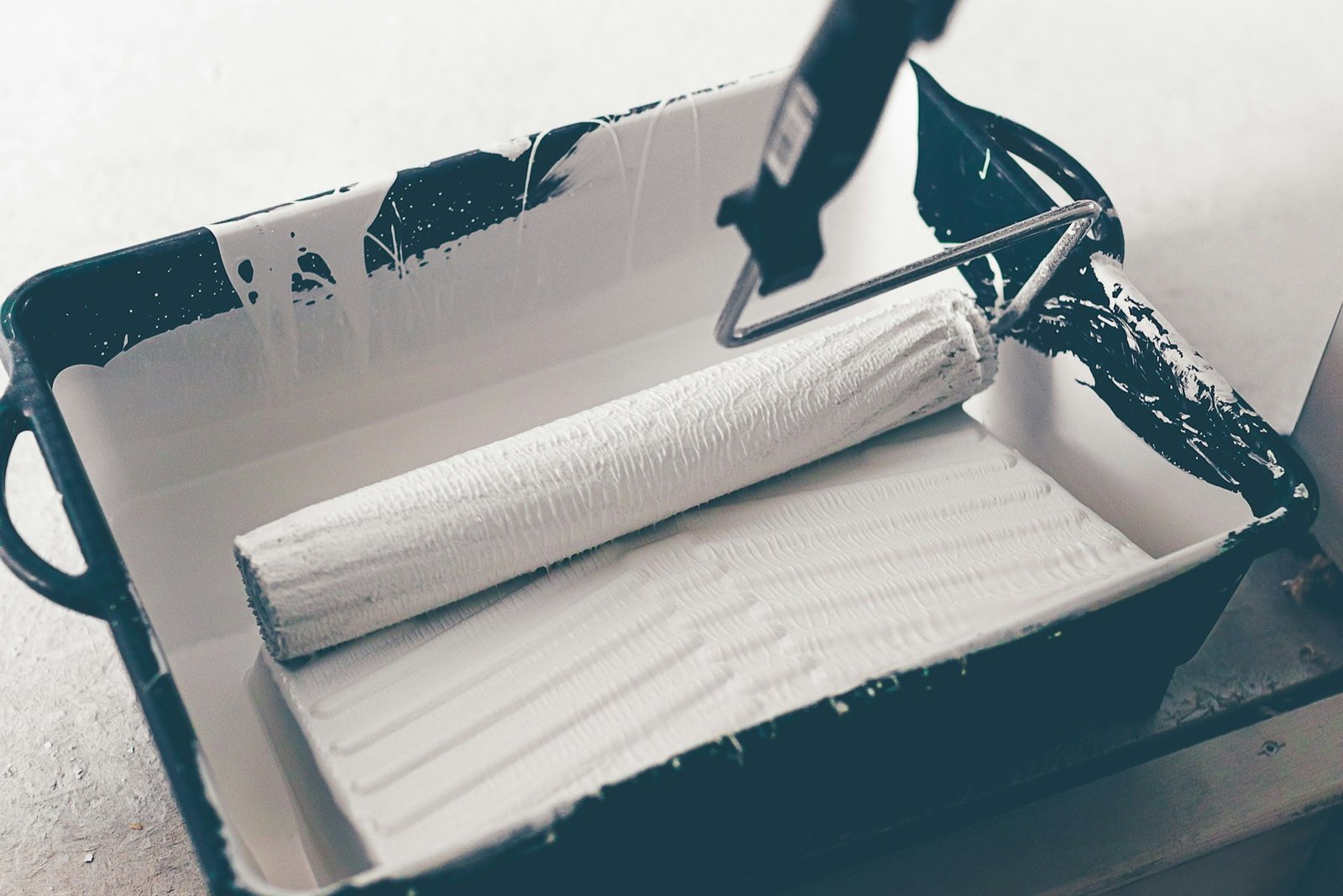 Farbroller wird mit weißer Farbe über eine Wand geführt