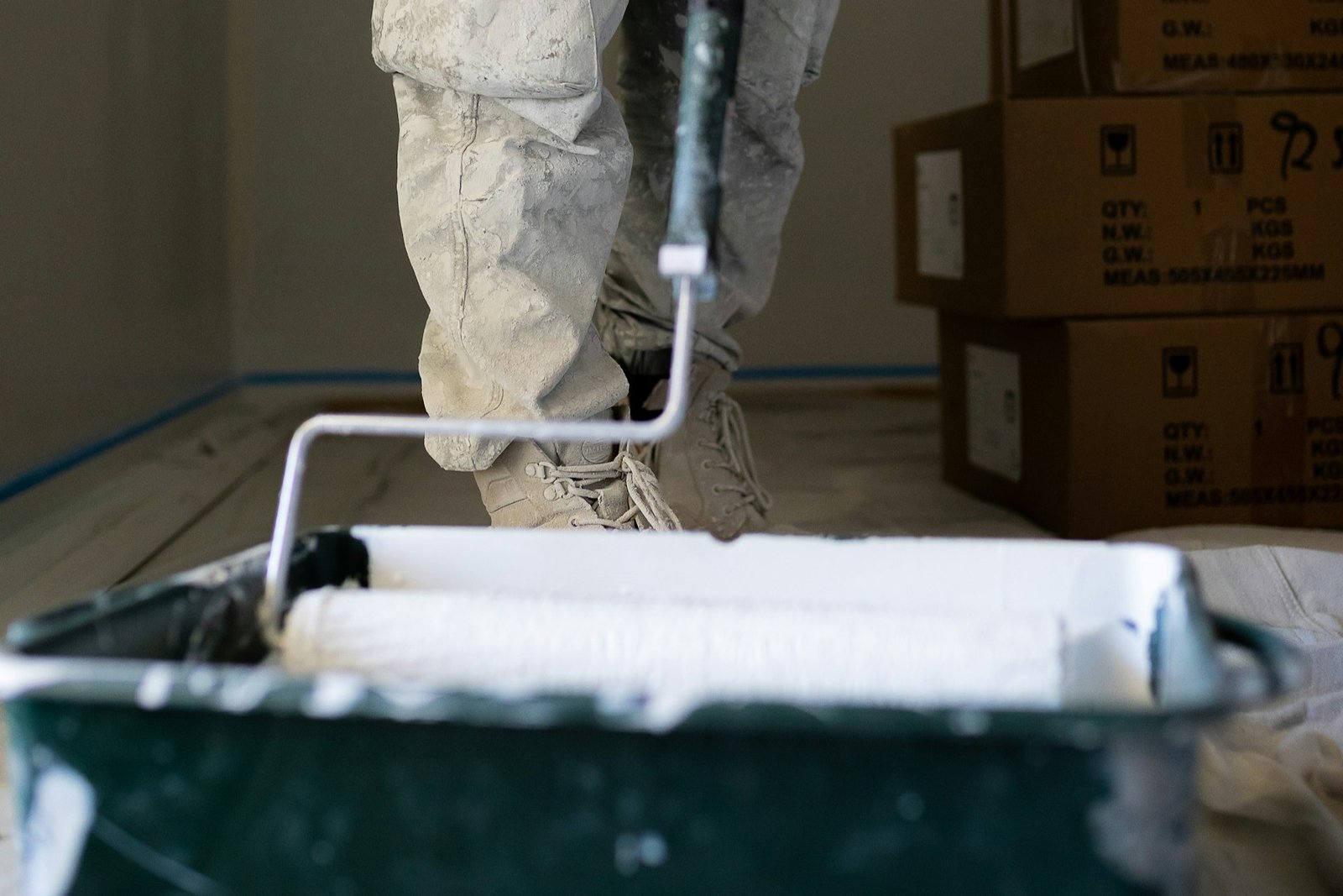 Farbroller trägt neue Farbe über eine bereits gestrichene Wand auf