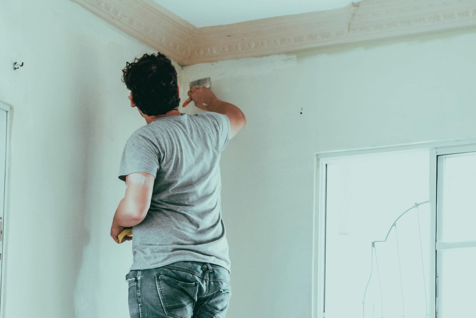 Farbroller trägt weiße Farbe auf eine Innenwand auf