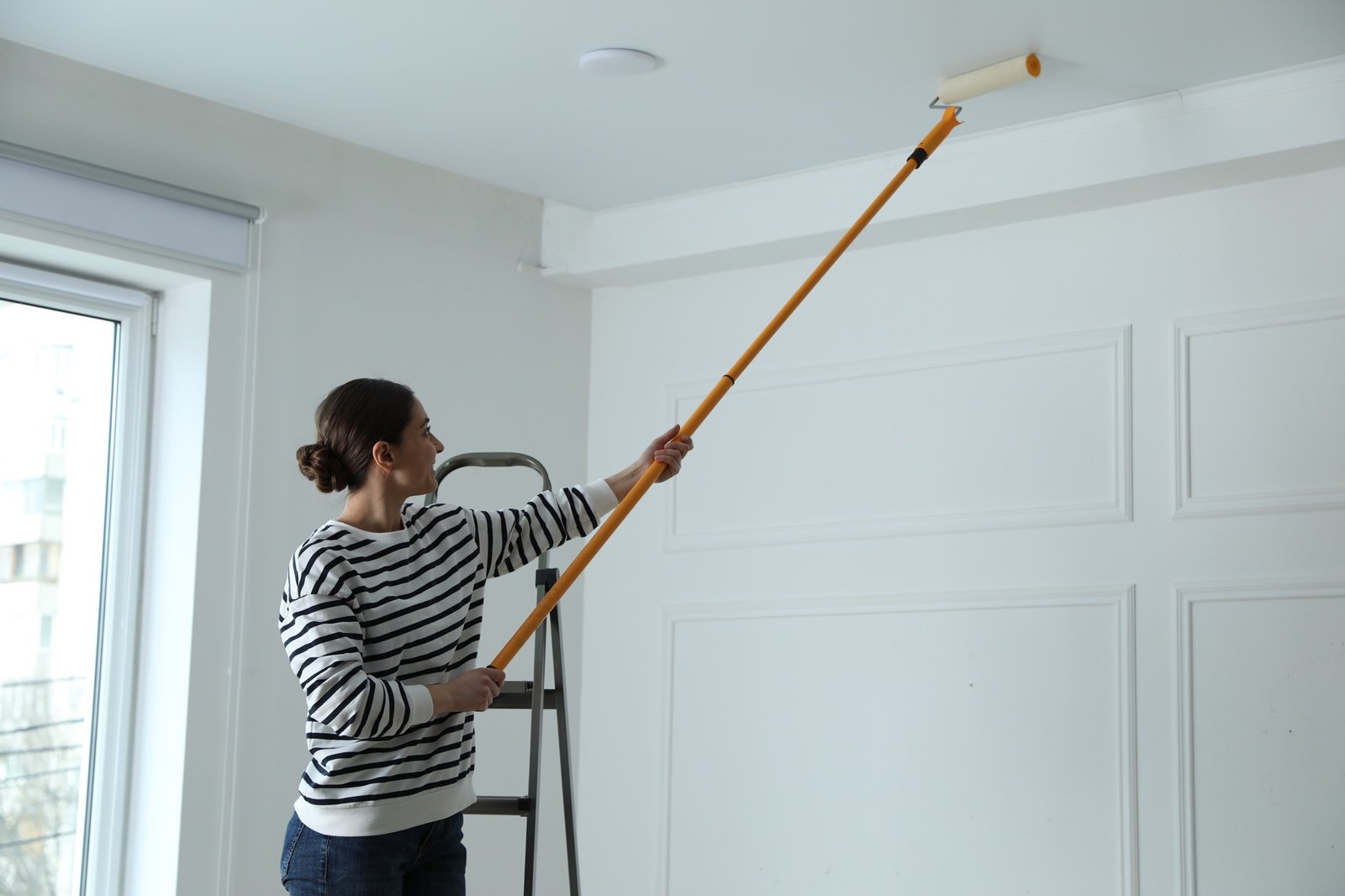 Decke wird mit weißer Farbe und Rolle gestrichen